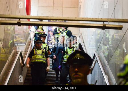 Londres, Royaume-Uni. 17 avr, 2019. Un changement de climat protestataire qui elle-même collée sur le toit d'un train DLR à Canary Wharf DLR Station est emmené par la police. Credit : Claire Doherty/Alamy Live News Banque D'Images