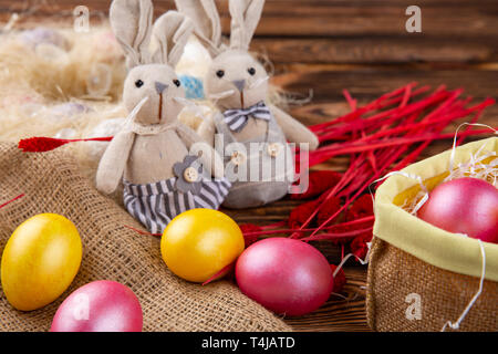 Les oeufs de Pâques colorés et lapin poupée sur fond en bois et un sac. Banque D'Images