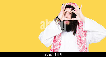 L'homme d'affaires arabe aux cheveux longs portant keffieh foulard traditionnel faisant forme de coeur avec la main et des doigts en souriant à par Banque D'Images