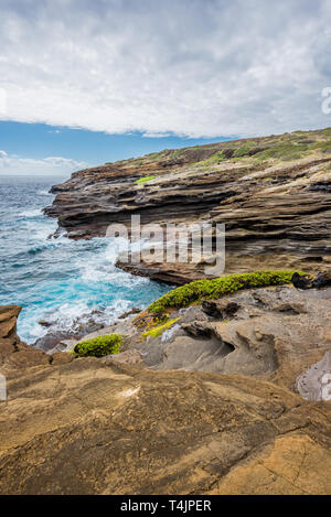 Les vagues de l'océan tourbillonnant autour de la roche de lave unique de formations le Lanai Lookout sur Oahu, Hawaii Banque D'Images