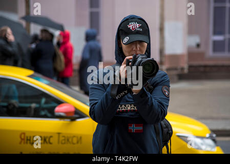 Avril 2019 , MOSCOU, RUSSIE. Photographe fille dans des vêtements sombres et une casquette de photographies sur les rues par temps humide Banque D'Images