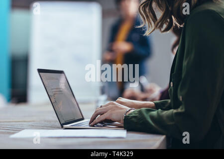 Cropped shot of woman working on laptop while sitting in meeting dans la salle de conférence. Ordinateur portable à l'aide de cadres de sexe féminin au cours d'une présentation en bureau. Banque D'Images