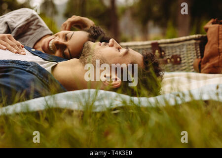 Jeune couple lying together sur couverture de pique-nique. L'homme et de la femme se détendre ensemble dans le parc. Banque D'Images