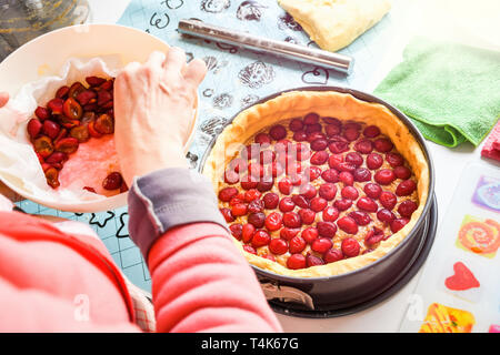 La préparation à la maison douce et fraîche cherry pie sur un comptoir de cuisine mettant à l'intérieur de cerise rouge dans la pâte crue Banque D'Images