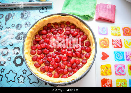 La préparation à la maison douce et fraîche cherry pie sur un comptoir de cuisine mettant à l'intérieur de cerise rouge dans la pâte crue Banque D'Images