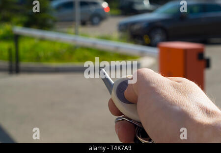 Une personne avec une télécommande ouvre une barrière automatique dans le stationnement en appuyant sur le bouton . Banque D'Images