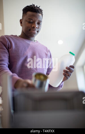 Teenage Boy le tri Recyclage dans bac de cuisine à la maison Banque D'Images