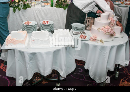 Garçon de restaurant servant des gâteaux de mariage avec table de desserts. Banque D'Images