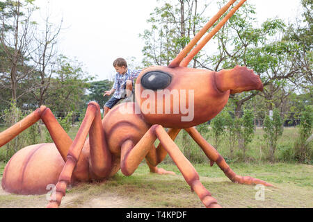 Heureux petit garçon jouant dans un parc en journée. Kid s'amusant à l'extérieur. Concept de bon gré. Banque D'Images