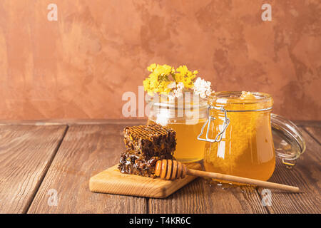 Miel parfumé frais dans un bocal en verre sur un fond de bois sur la table. Différents types de miel d'abeilles. Produits naturels. Banque D'Images
