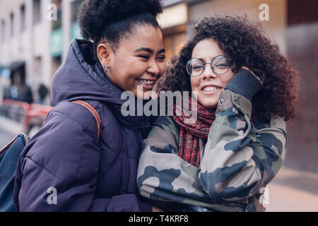 Deux jeunes femmes serrant dans la rue avec des cheveux bouclés - gai, d'amitié, de la bonne humeur Banque D'Images