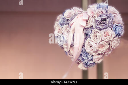 Forme de coeur bouquet fait de fleurs différentes accroché sur un mur Banque D'Images