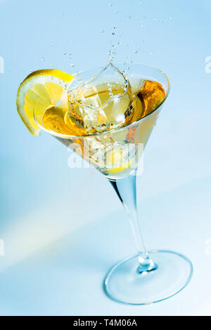 Éclaboussures d'olive sur un verre de martini avec une tranche de citron Banque D'Images