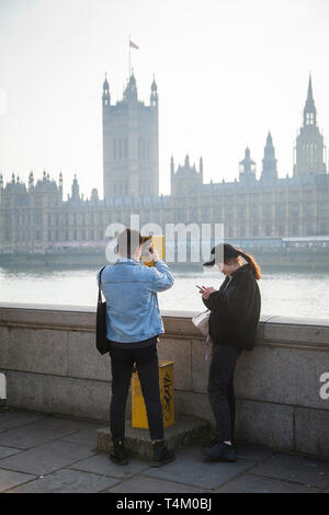 Deux jeunes touristes étrangers regarder en face, les chambres du Parlement sur la Tamise Banque D'Images