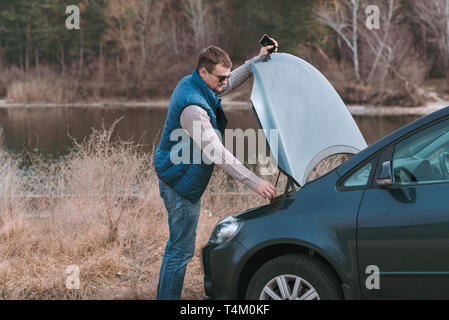 Les jeunes bel homme ayant problème avec voiture et appeler à l'aide. Banque D'Images