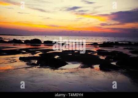 Ciel avec des nuages suspendus et les boues humides durant la marée basse couverte de jaune et rouge, la lumière vive pendant le coucher du soleil on tropical island Ko Lanta, Th Banque D'Images