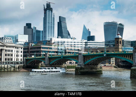 Bateau touristique mercie passant sous Southwark Bridge sur la Tamise, avec l'emblématique d'immeubles de grande hauteur à l'arrière-plan. Banque D'Images