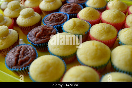 Un bac plein de petits gâteaux. Une rangée de chocolat blanc central, et d'autre avec et sans la couverture hat. Arrière-plan flou. Banque D'Images