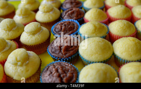 Un bac plein de petits gâteaux. Une rangée de chocolat blanc central, et d'autre avec et sans la couverture hat. Arrière-plan flou. Banque D'Images