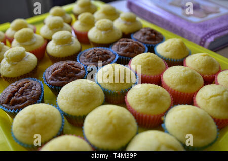 Un bac plein de petits gâteaux. Une rangée de chocolat blanc central, et d'autre avec et sans la couverture hat. Arrière-plan flou. Banque D'Images
