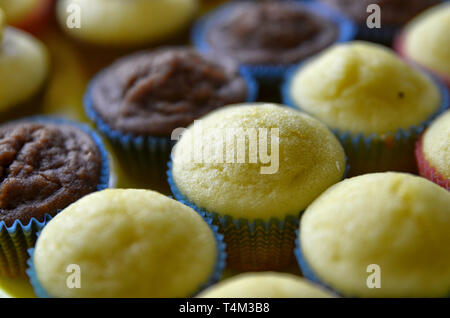 Un bac plein de petits gâteaux. Une rangée de chocolat blanc central, et d'autre avec et sans la couverture hat. Arrière-plan flou. Banque D'Images