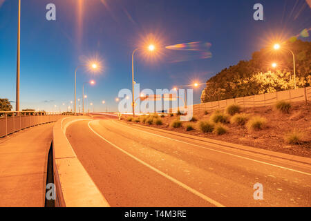 Tauranga Harbour Bridge sur la rampe d'accès à l'aube avec l'éclairage de rue et des véhicules de passage des temps d'exposition. Banque D'Images
