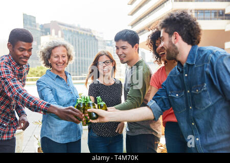 Groupe d'amis dans le grillage avec une bouteille de bière sur un toit de maison Banque D'Images
