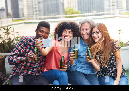 Les amis de boire une bière pendant leur temps libre, prendre un avec leur smartphone selfies Banque D'Images