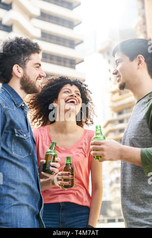 Trois étudiants en amis célébrer avec une partie de la bière sur un toit de maison dans la ville Banque D'Images