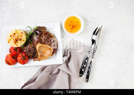 L'osso bucco de boeuf avec de la purée de pommes de terre et les tomates de table. Plat avec la viande. Vue de dessus, copy space Banque D'Images