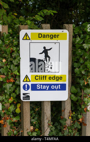 Un signe d'avertissement les marcheurs à proximité d'un bord de la falaise sur le sentier du littoral entre Broadstairs et Ramsgate, Kent, UK. Banque D'Images