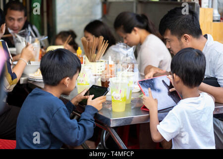 Enfants jouant sur des tables à l'heure des repas sur le côté près de la rue du marché de PSAR O Russei, Phnom Penh, Cambodge, Asie du Sud, Asie Banque D'Images