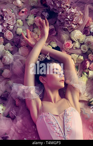 Affection. Vue de dessus de la belle jeune femme en rose ballet tutu entourée de fleurs. L'humeur du printemps et de la tendresse dans les récifs de la lumière. Art photo. Concept de printemps, fleurissent et l'éveil de la nature. Banque D'Images