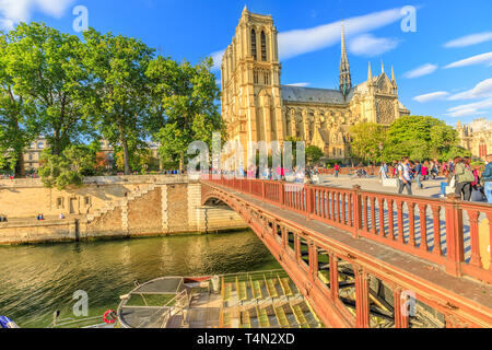 Paris, France - 1 juillet 2017 : Bateaux-Mouches bateau amarré sur la Seine sous le pont rouge avec la Cathédrale Notre Dame sur l'Ile de la Cité dans un endroit ensoleillé Banque D'Images