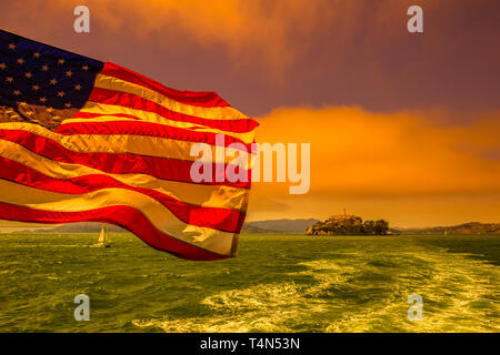 Ferry pour Alcatraz avec le drapeau américain. L'horizon de la baie de San Francisco, Californie, États-Unis. Sur la mer du bateau à l'Alcatraz au coucher du soleil. Banque D'Images