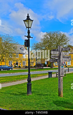 Style ancien en bois patiné lampadaire et panneau au centre de la village de Cotswold parfaite de Broadway. Banque D'Images