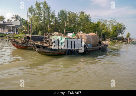 Les bateaux-dragons en bois traditionnel avec des filets de pêche sur le bord du delta du Mékong Vietnam rural. Banque D'Images