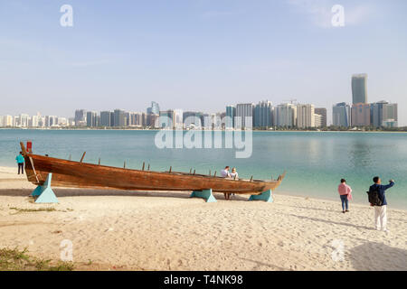 ABU DHABI, ÉMIRATS ARABES UNIS, LE 10 JANVIER 2019 : les touristes sont photographiés sur la rive de la baie sur le fond d'un vieux bateau en bois et un beau panorama o Banque D'Images