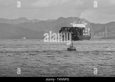 Photo en noir et blanc du porte-conteneurs KOTA LUKIS, quitte les terminaux à conteneurs Kwai Tsing à Hong Kong et se dirige vers le canal East Lamma Banque D'Images