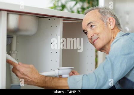 L'homme principal travaillant sur l'installation de plomberie de cuisine Banque D'Images