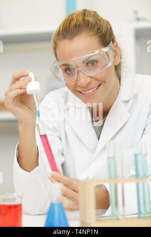 Happy young woman technicien utilise une pipette dans un laboratoire Banque D'Images