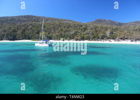 Jour frisquet sur Wineglass Bay en Tasmanie. Seulement un seul yacht flottant dans les eaux claires comme du cristal Banque D'Images