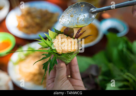 La salade d'herbe particulière à Kon Tum, Vietnam. En utilisant les feuilles pour faire un récipient en forme de cône pour mettre la nourriture et l'utilisation du bacon, crevettes frites, Coupe Banque D'Images