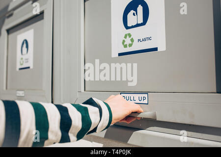 Une personne ouvre ou ferme un bac moderne des déchets pour la collecte séparée des déchets. Banque D'Images