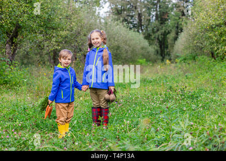 Un garçon et une fille sont maintenant les carottes et betteraves en leurs mains, juste à se rassembler dans le jardin. Des légumes fraîchement cueillis. Banque D'Images