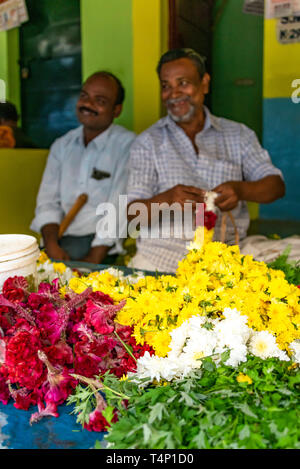 Vue verticale d'hommes faisant de guirlandes à Mattuthavani marché aux fleurs à Madurai, Inde. Banque D'Images