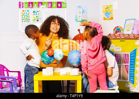 Les enfants divers groupe découvrez les planètes en nursery school Banque D'Images