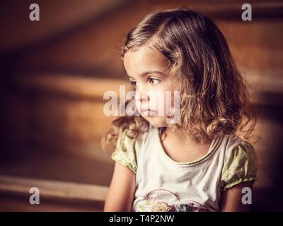 Fille, 3 ans, assis sur les escaliers, le regard mélancolique, Portrait, Allemagne Banque D'Images