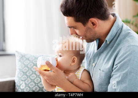 Famille, de la parentalité et de personnes concept - père bébé fille donnant à boire de la bouteille Banque D'Images