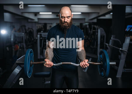 Athlète musculaire dans les vêtements de sport prend du poids, la formation dans une salle de sport. Homme barbu sur entraînement dans sport club Banque D'Images